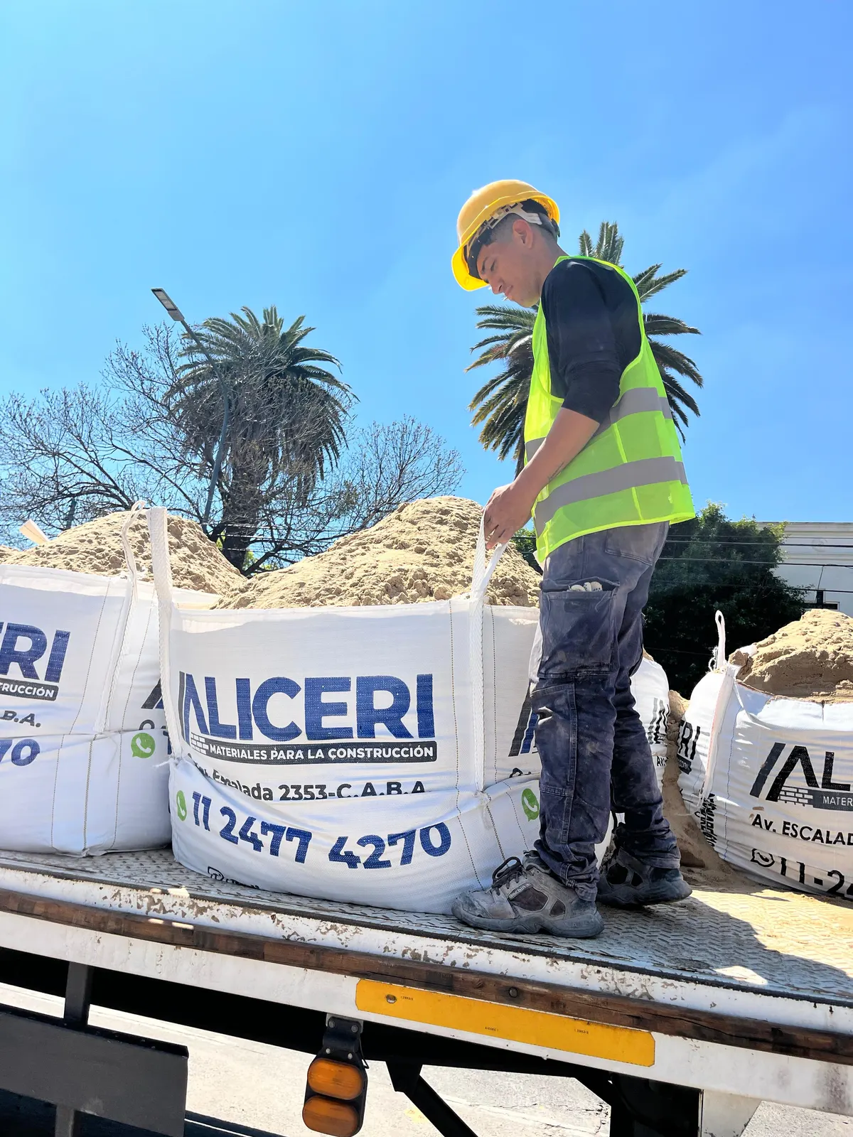 Operario de Aliceri con casco preparando un bolsón de arena sobre el camión